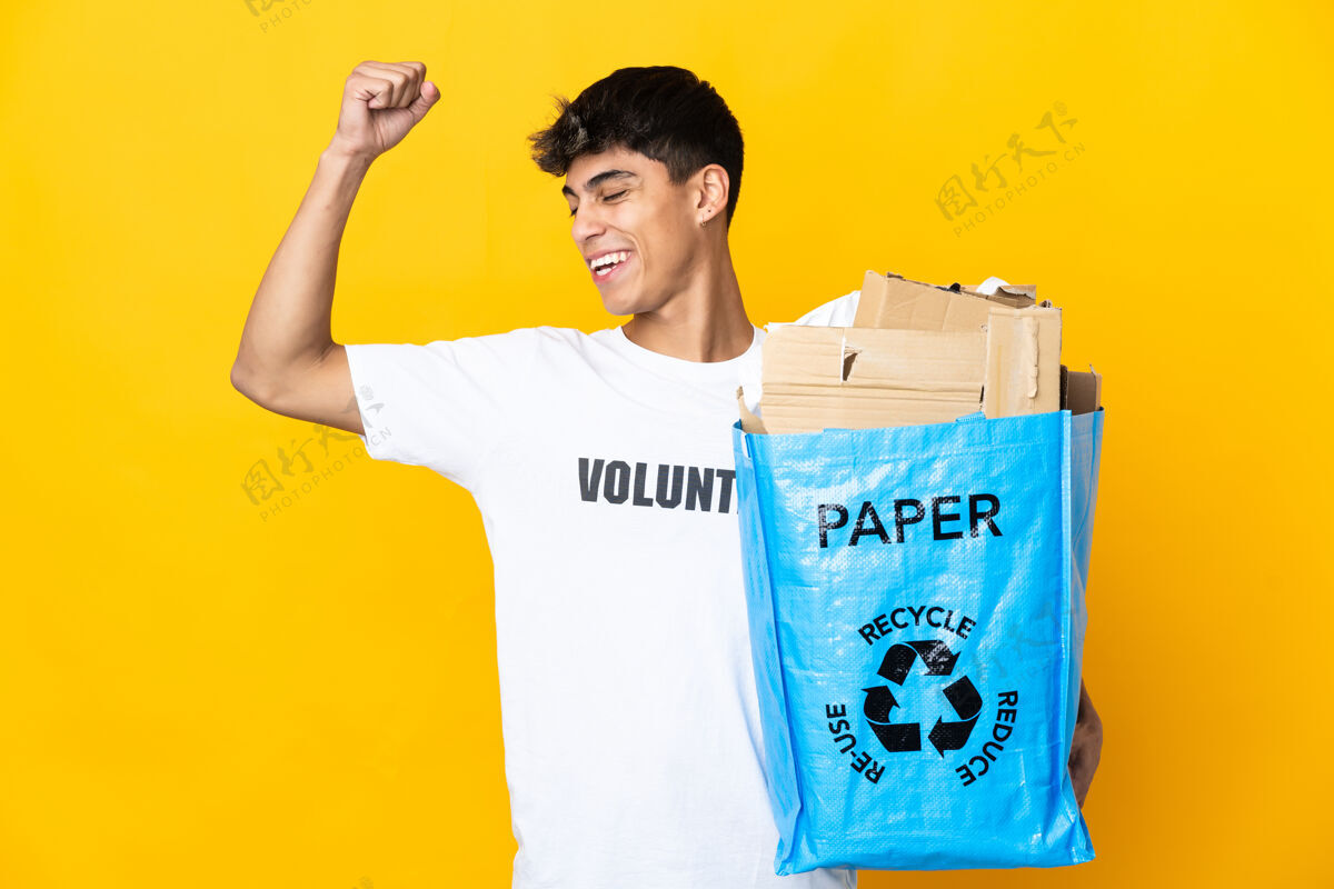 志愿者一个人拿着一个装满纸的回收袋 在孤立的黄色背景上进行回收 庆祝胜利责任彩票欢呼