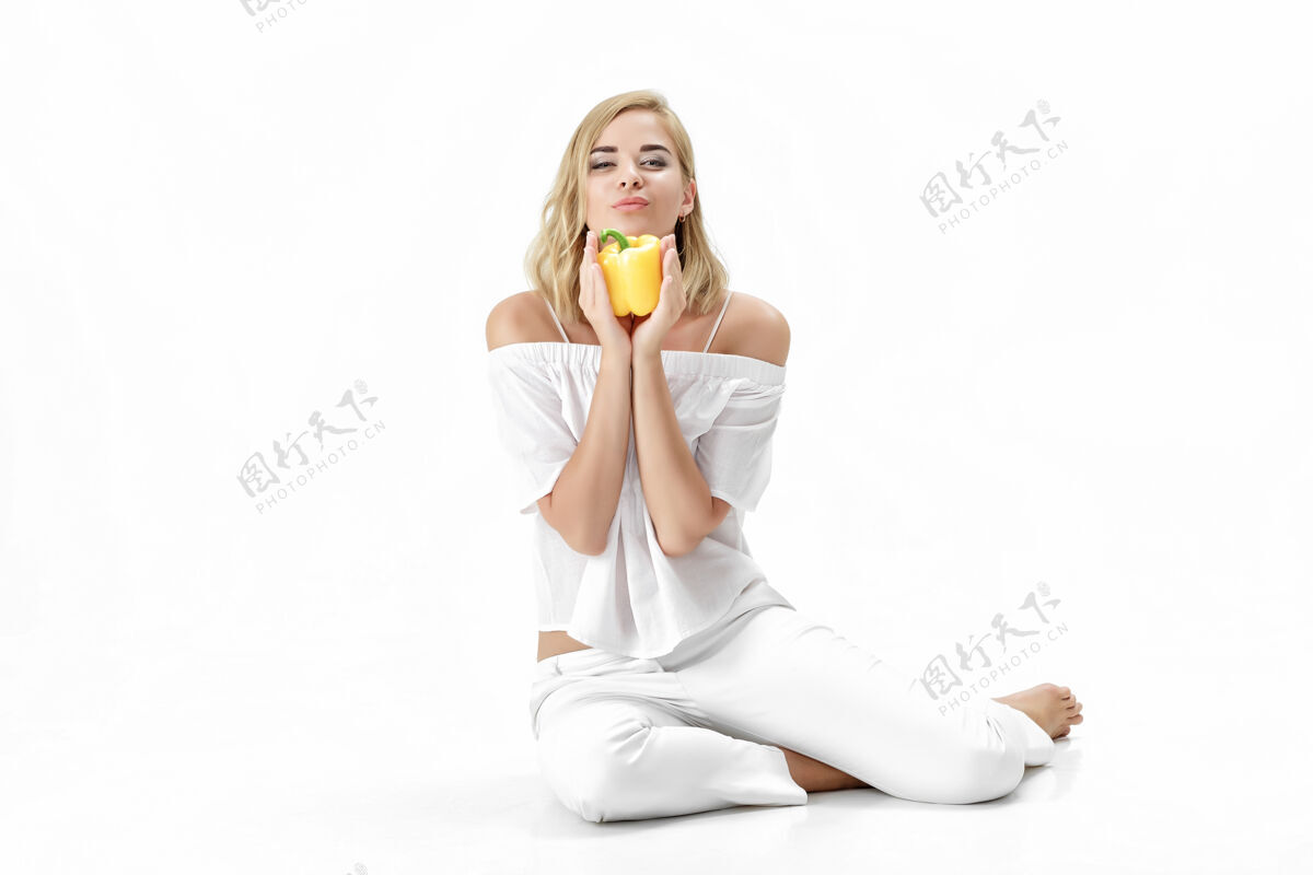 体重美丽的金发女人穿着白色上衣拿着黄色的铃铛胡椒粉健康节食和节食蔬菜生活方式女人