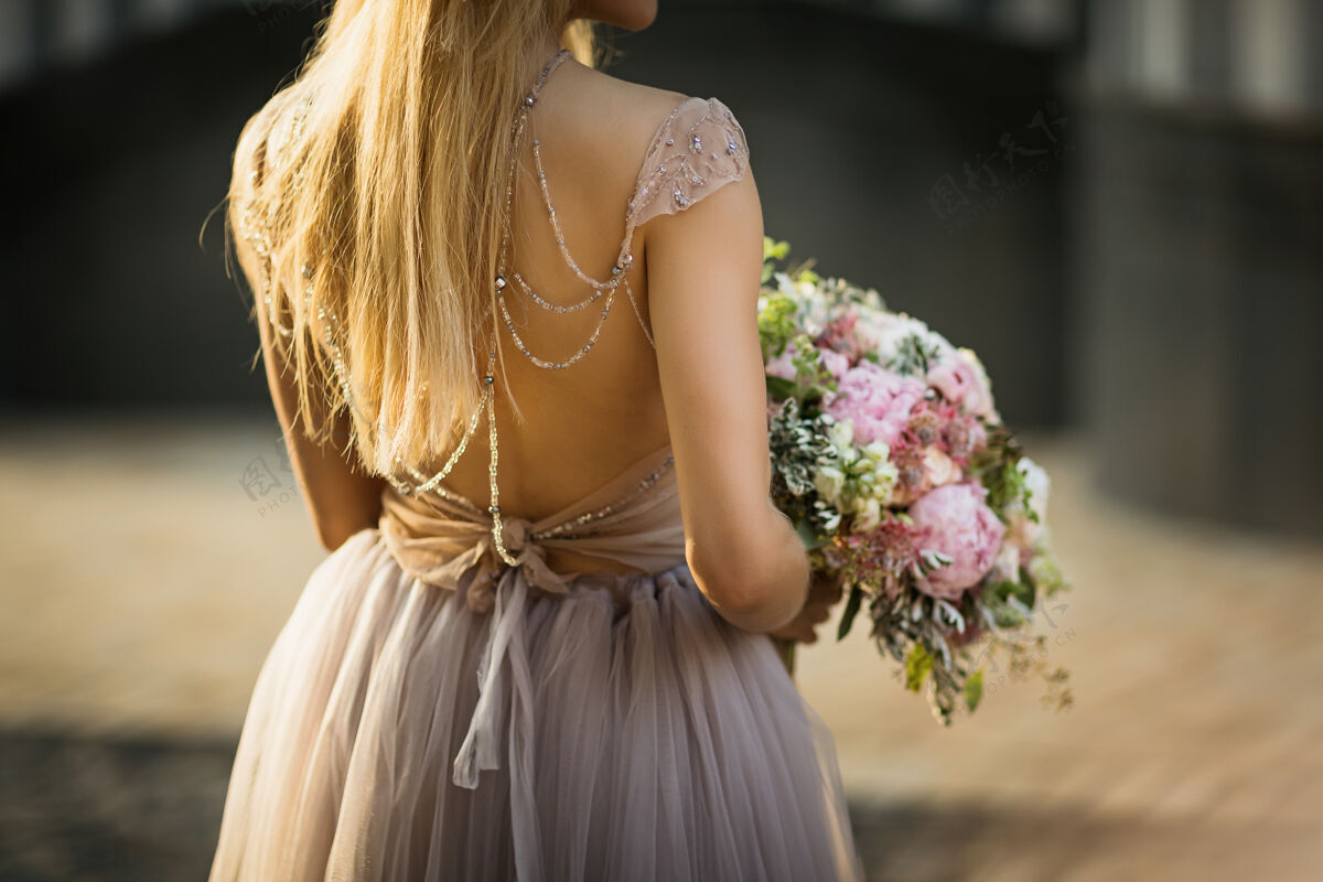 女孩新娘穿蕾丝婚纱回来了女装捧着一束柔和的鲜花和绿叶未婚夫花店花