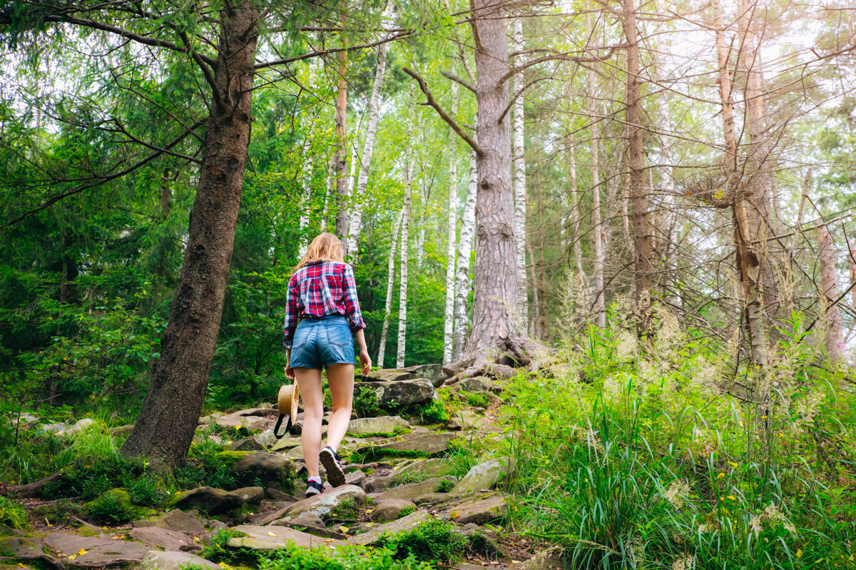徒步旅行时尚女孩山时尚戴草帽穿格子衬衫的女人森林流浪癖概念时髦人苔藓