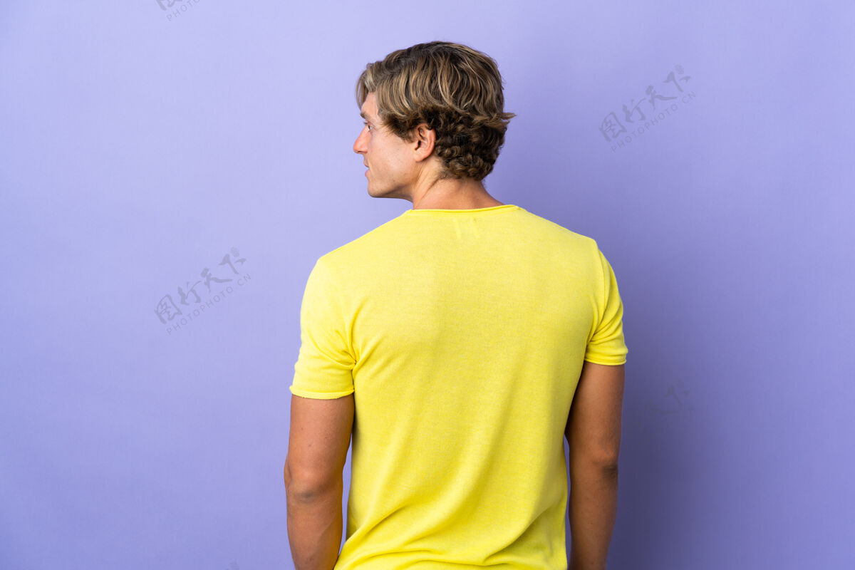 美国英国男子在孤立的紫色背景下 在后面的位置和看一边背部成人长相