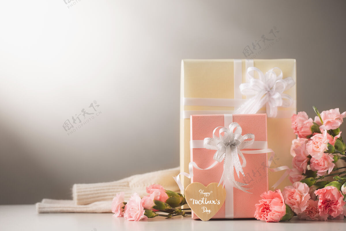 爱静物与甜蜜的康乃馨花和礼物放在桌上 母亲节的概念墙礼物卡片