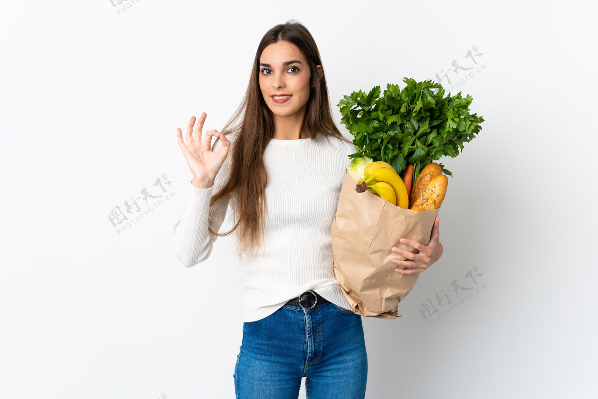 营养年轻的白种女人在买一些白色背景的食物 用手指显示ok标志生的积极食物