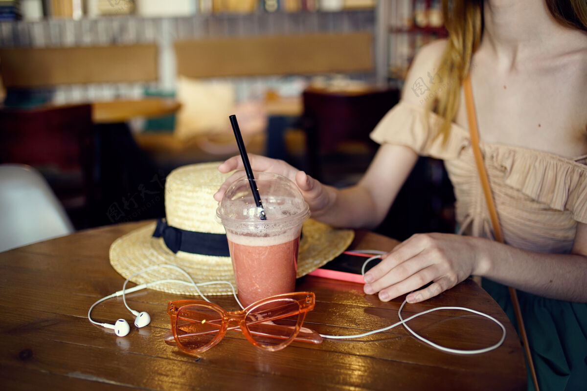 手机一个女人带着耳机坐在餐厅里一杯新鲜的玻璃杯休闲消遣女士休闲手机