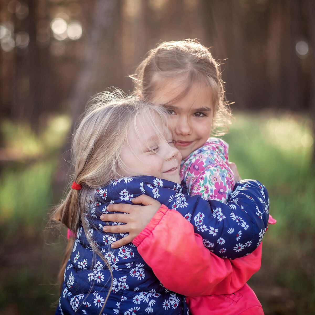 高兴可爱的女孩在秋天的森林里散步 用爱和温柔拥抱着她的小妹妹 全国拥抱和友谊日 休闲的生活方式 户外享受候选人秋天