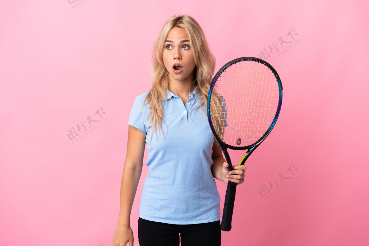球拍年轻的俄罗斯女子打网球孤立在紫色做惊喜的手势 同时向一边看担心脸健康