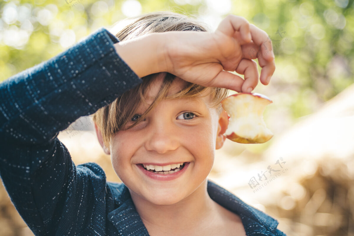 乐趣一个在农场过秋假的孩子一个微笑的男孩一只手拿着一个被咬的苹果孩子吃了笑