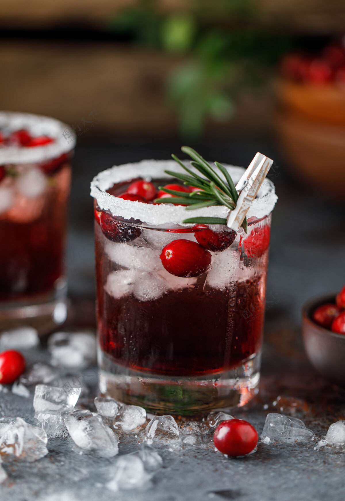 凉红莓鸡尾酒冰圣诞节红莓饮料在玻璃装饰糖和迷迭香配料冷饮料