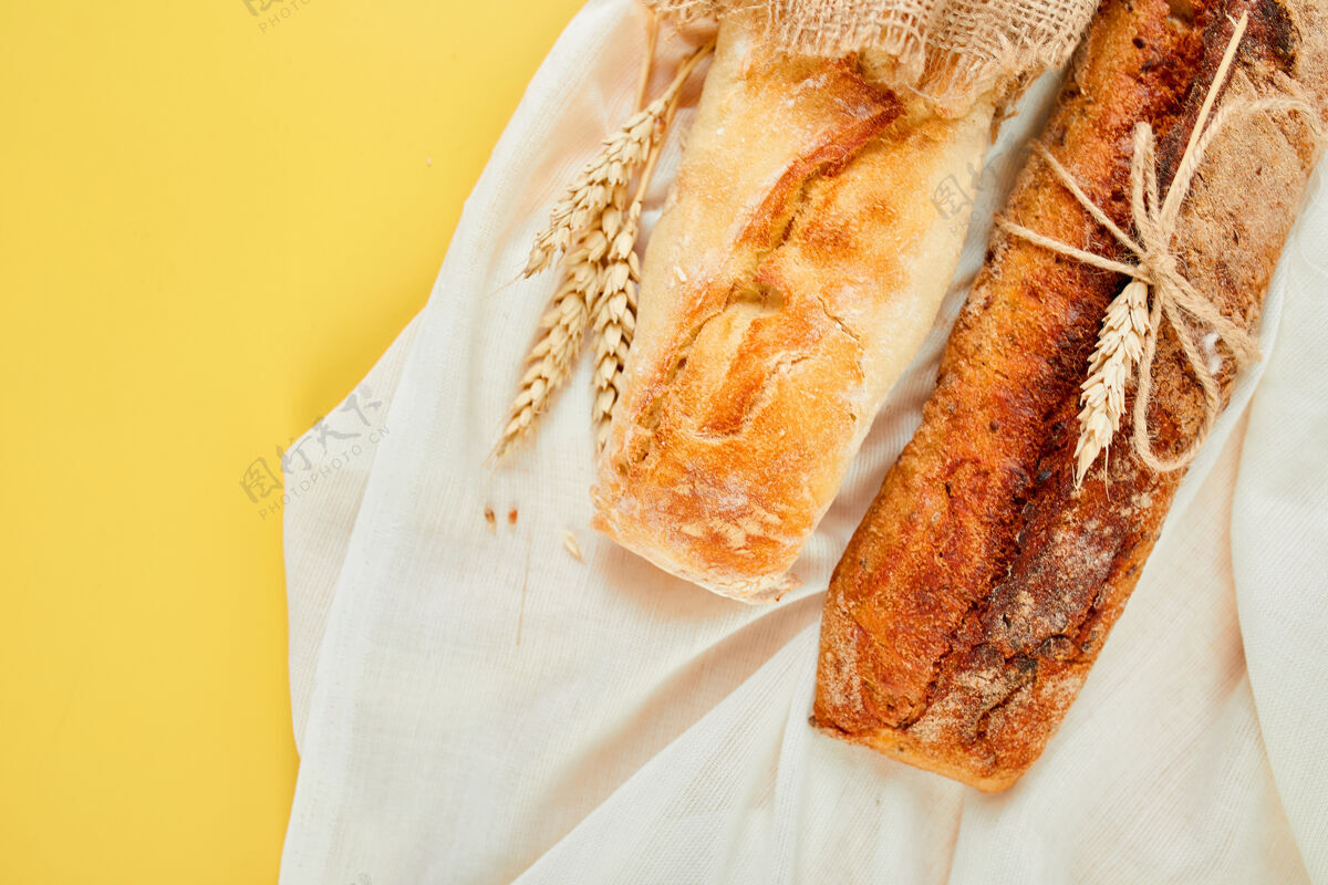 篮子黄色表面上两个法式面包的俯视图烘焙特写本地