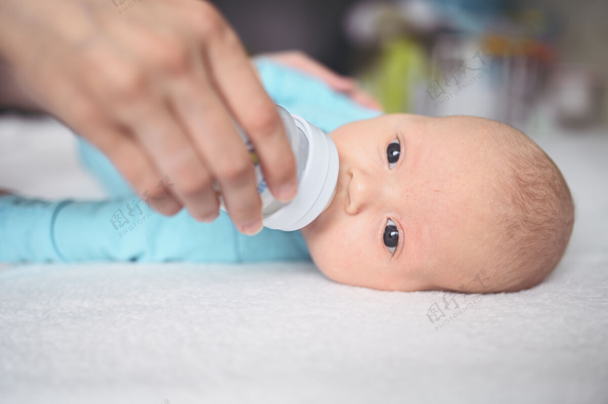新生儿可爱动情搞笑的新生男孩抱着奶瓶躺在床上托儿所婴儿奶瓶健康