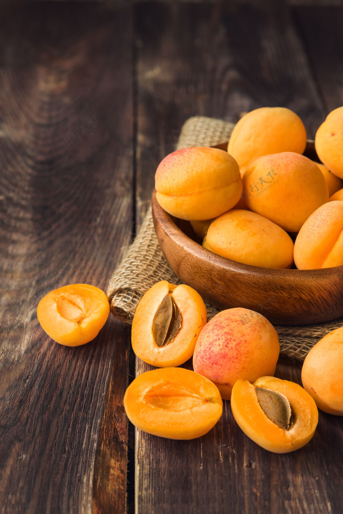 团体新鲜的有机杏子放在木制碗里 放在质朴的木头上甜点黄色夏天
