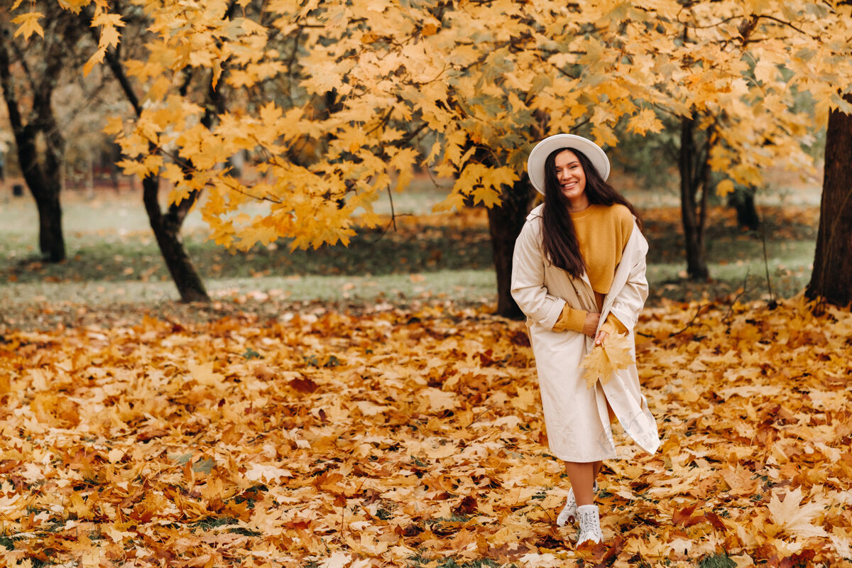 公园一个穿着白外套戴着白帽子的女孩在秋天的公园里微笑自然肖像一起