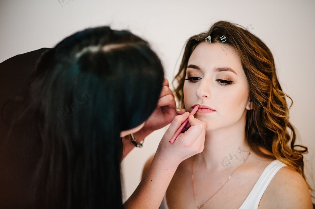 手化妆概念化妆师在脸部和皮肤上做完美的化妆模型发型师用嘴唇画嘴唇铅笔漂亮女人接近-起来女孩女人新娘