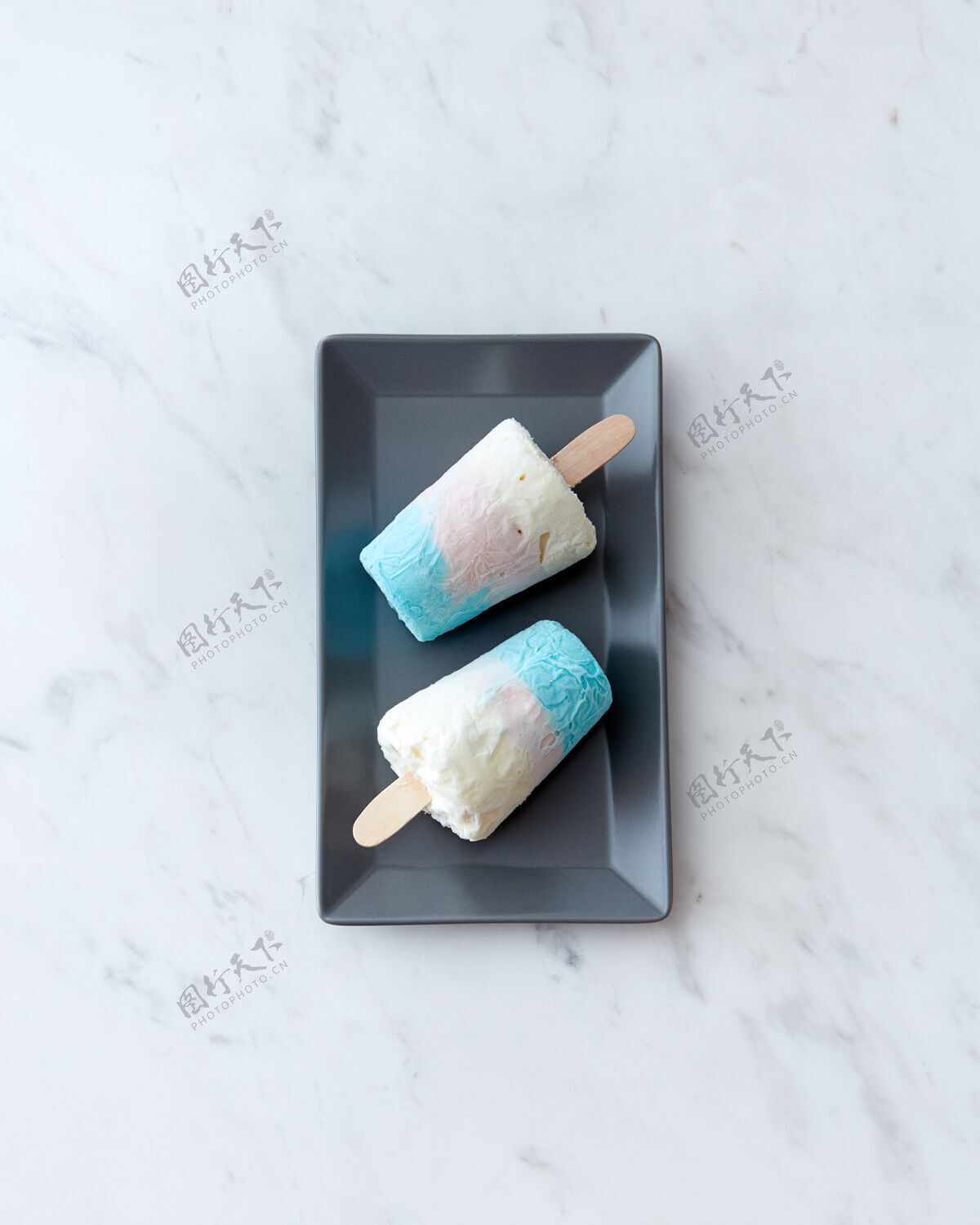 棒在一个黑色盘子里 两个自制的健康冰淇淋棒棒糖放在一张灰色大理石桌子上 上面放着一份空间冷甜点平底躺下草莓汽水冰