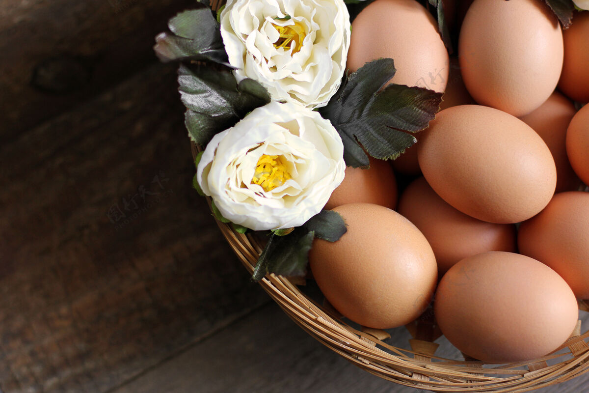 四月鸡蛋和花放在木桌上的篮子里传统鲜花食物