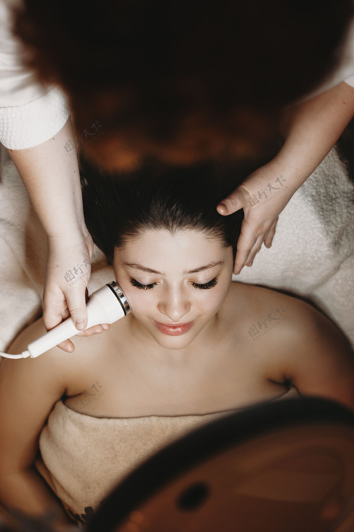 医疗一位美容师在健康spa中心为一位可爱的女士进行电穿孔治疗的俯视图皮肤特写治疗