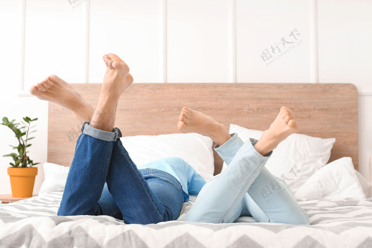 床躺在家里床上的年轻夫妇房子家庭腿