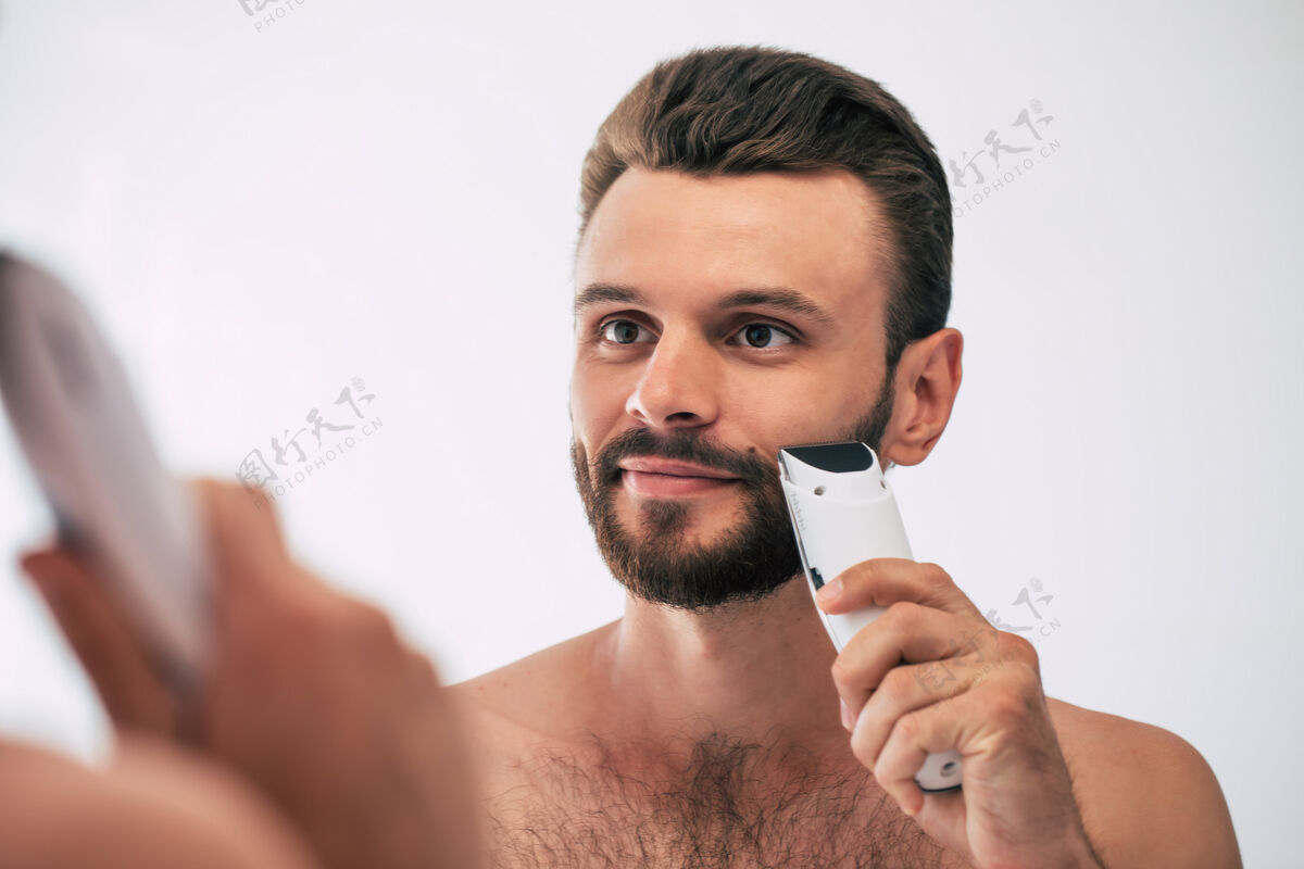 成人英俊的年轻人在街上刮胡子浴室.肖像一个时髦的裸体胡须男人在家里的镜子里检查他的脸理发师肌肉男人