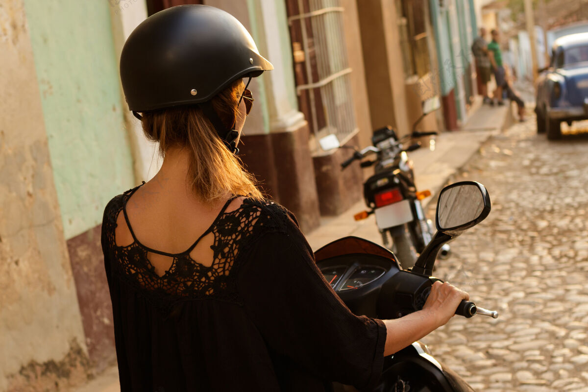 黑人在老城区街道上开着摩托车的女旅行者度假城镇户外