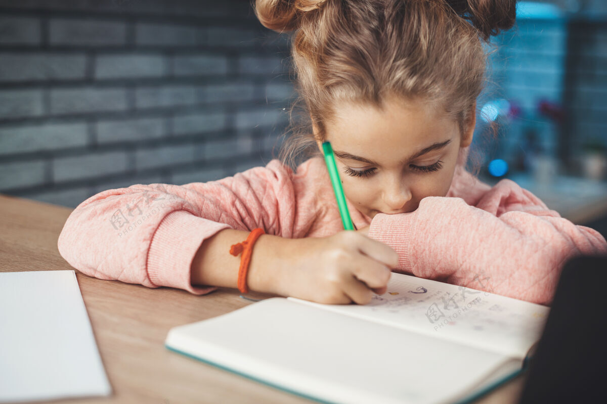 电脑一个金发小女孩坐在厨房桌子旁 在笔记本上画东西的特写照片房子幼儿园小学生