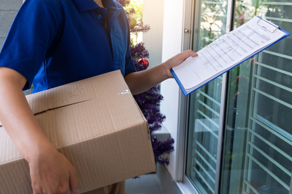 包装身穿蓝色制服的送货员为客户递包裹箱目的地购买微笑