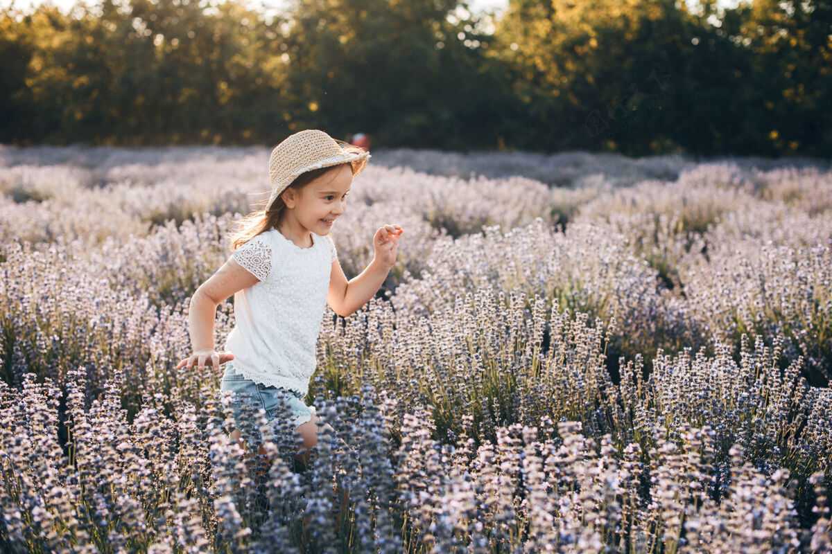 玩耍美丽的小女孩戴着帽子在花丛中奔跑 在夕阳下欢笑孩子童年日落