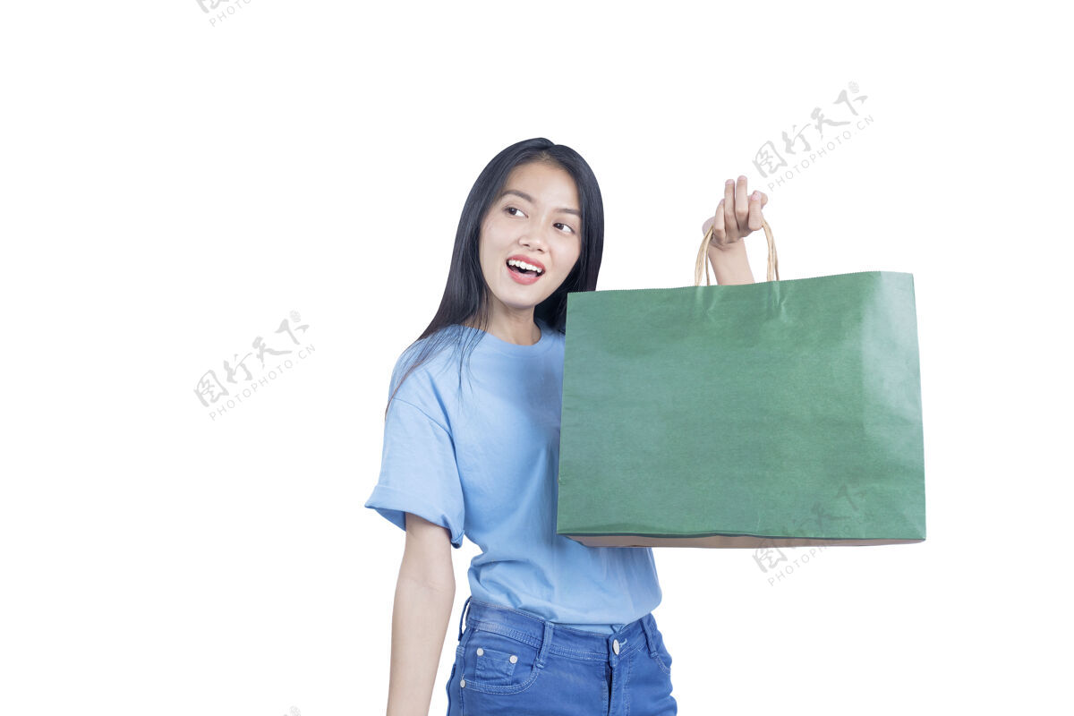 包亚洲女人拎着购物袋隔着白墙买家女士购物狂