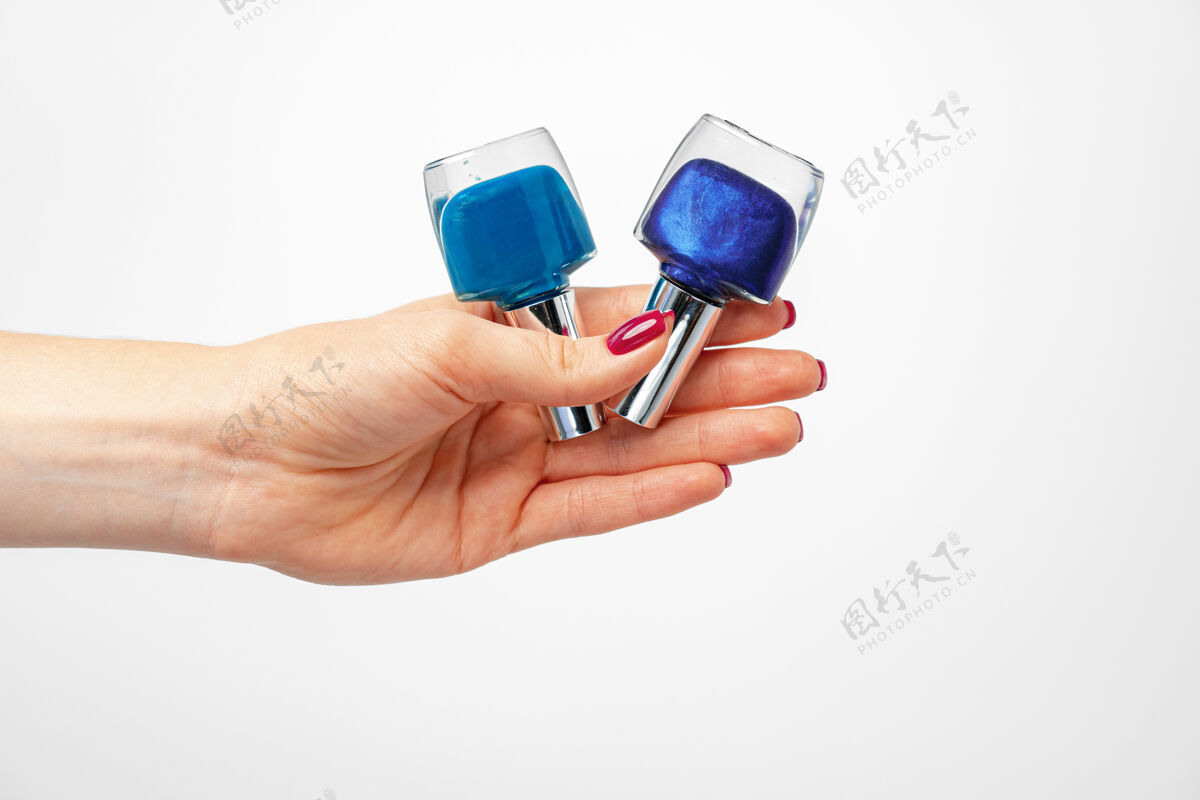 护理女性手拿蓝色指甲油对着白色特写女孩瓶子团体