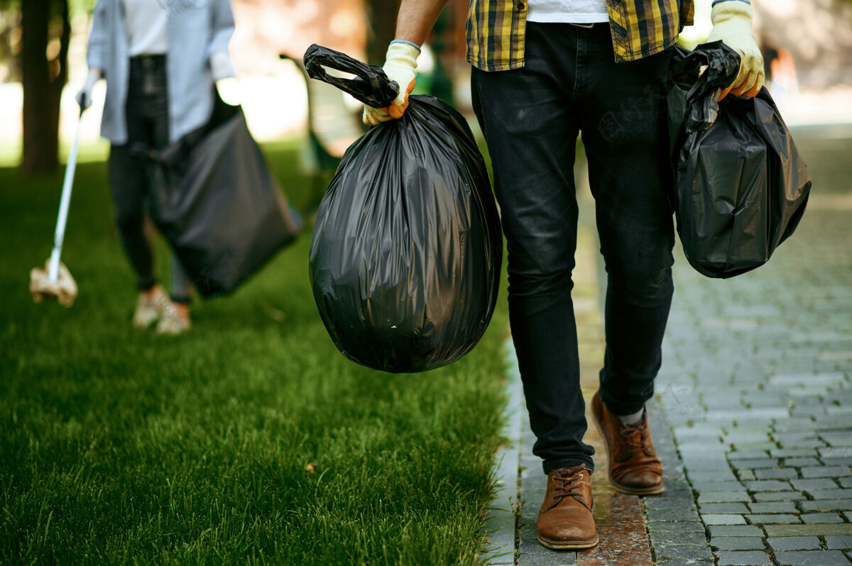 护理年轻人在公园里拿着塑料垃圾袋 志愿服务男人清林 生态修复 生态生活方式 垃圾回收 生态关怀垃圾挑选森林