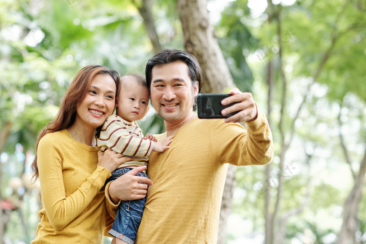女人快乐积极的亚洲男人与他美丽的妻子和可爱的小儿子自拍手机孩子男人
