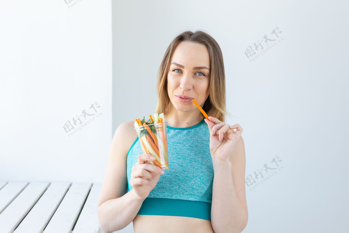沙拉饮食理念-健活方式女人吃蔬菜微笑快乐室内年轻女人吃东西白色人女性