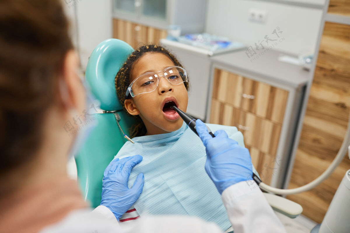 牙科小女孩张着嘴躺在牙科椅上 牙医在医院做牙齿和口腔卫生工作牙医牙科助理