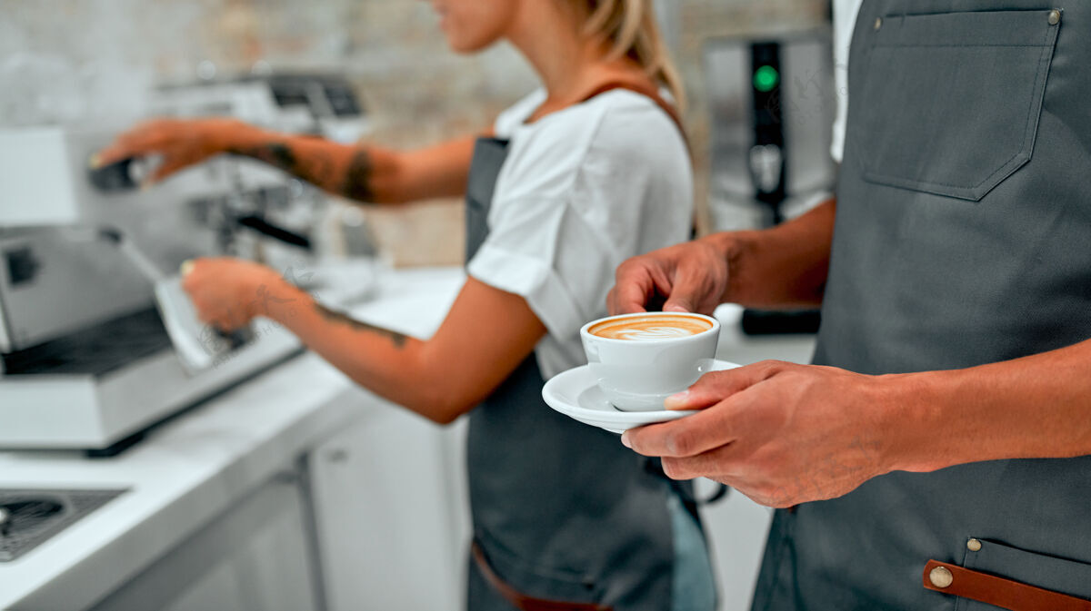 杯子美丽的白种女人和非洲男咖啡师正在咖啡店里煮咖啡职业便携式过滤器非洲