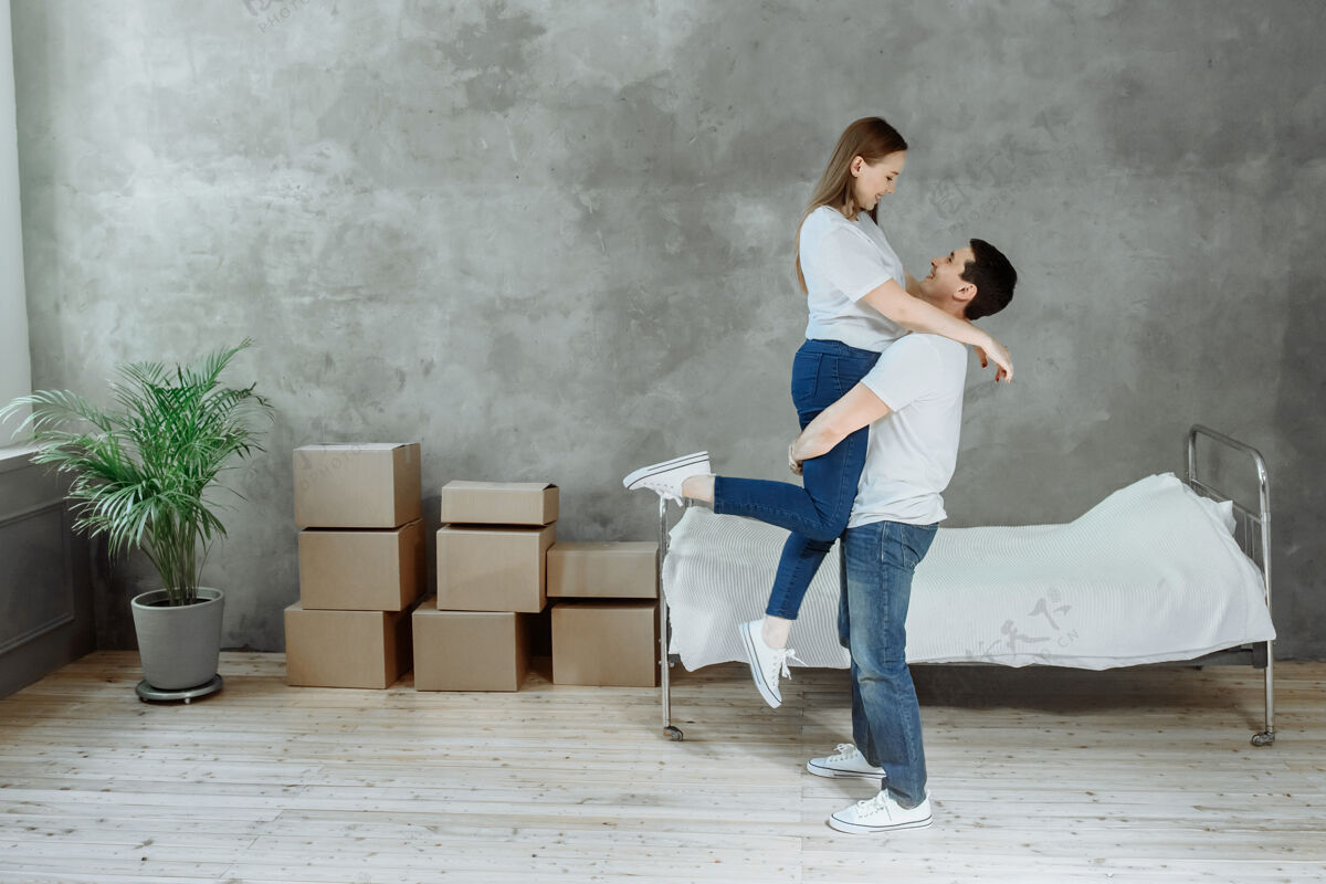 许多年轻幸福的夫妻男女在房间里搬箱子在家拥抱男人生活