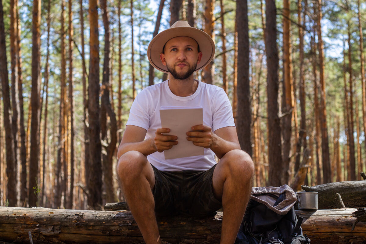 徒步旅行露营时戴帽子的人手里拿着地图徒步旅行在山上 森林里时髦成人表达