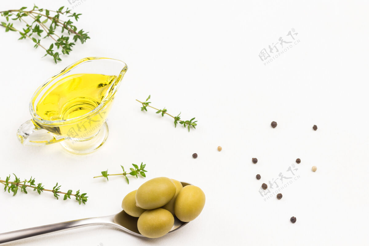 水果金属绿橄榄勺子橄榄玻璃中的油百里香小枝顶部查看油处女开胃菜