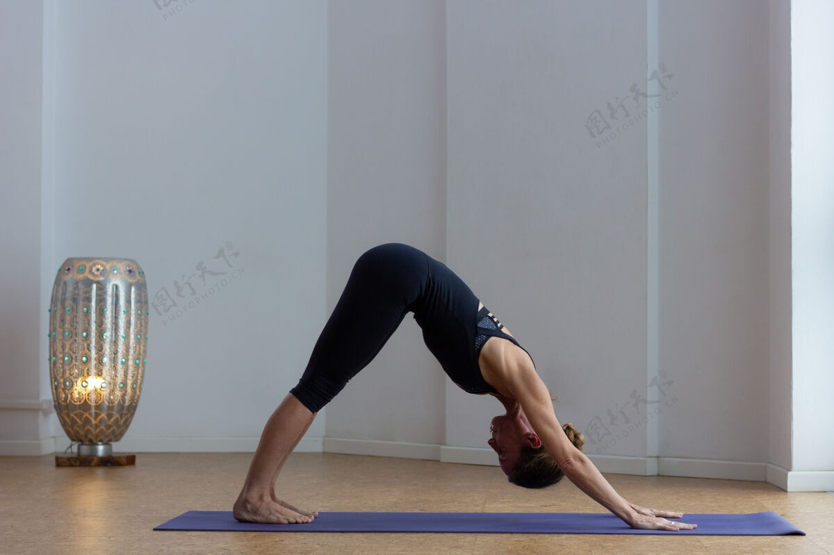 垫子苗条的女人在做adhomukhasvanasana瑜伽姿势女工作室下犬式体位瑜伽室内.停留健身 家庭训练课程健身人锻炼