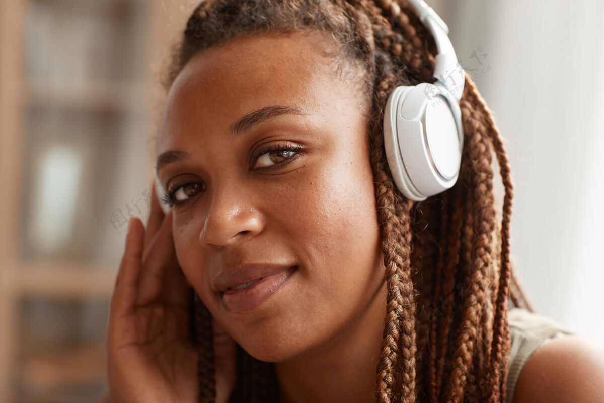 美女非洲年轻女子戴着无线耳机 留着时尚发型的特写镜头耳机音乐享受