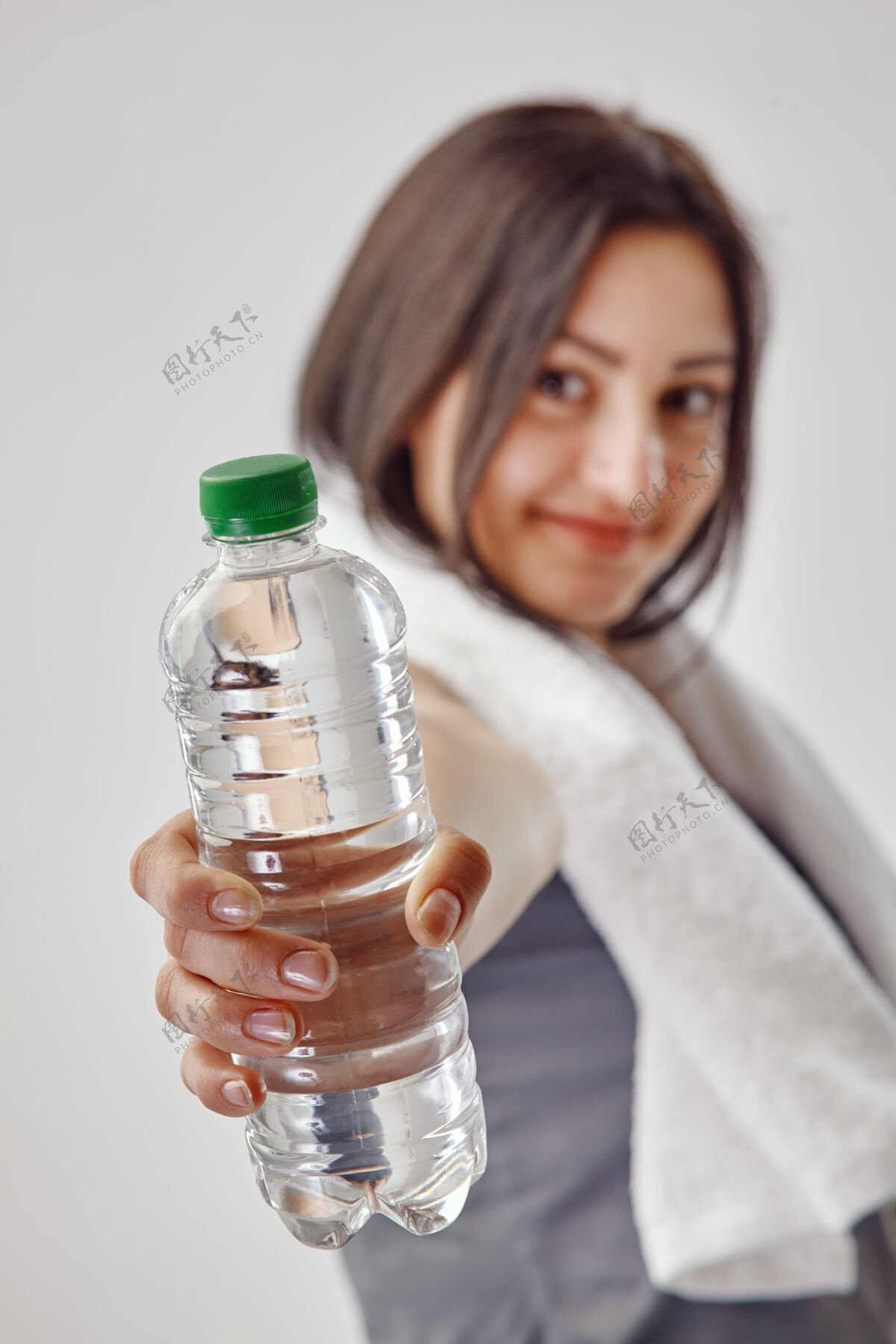 瓶子身穿灰色T恤的年轻黑发女子 脖子上围着白毛巾 手里拿着一瓶水头发新鲜女人
