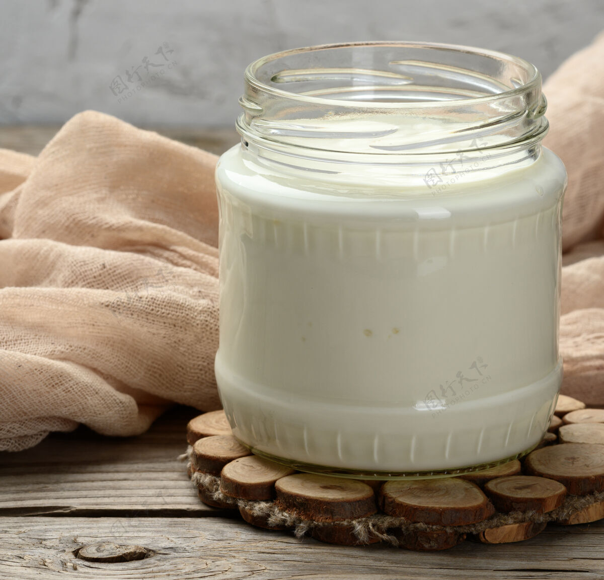 希腊语自制酸奶放在木制桌子上的透明玻璃罐里 是一种健康的发酵乳产品营养食物蛋黄酱