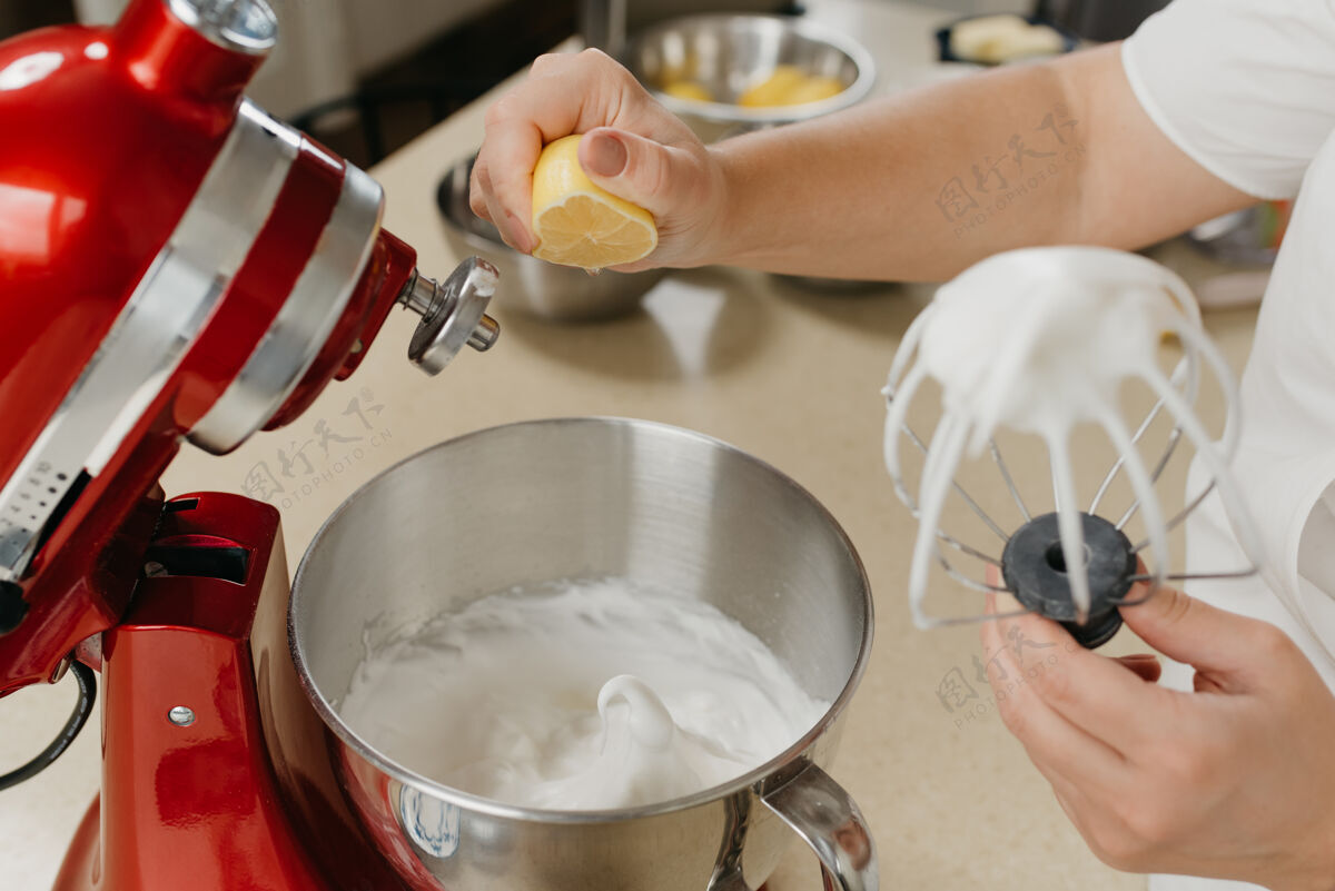 鸡蛋一张照片是一个女人在厨房里用不锈钢碗将柠檬汁碾碎成混合的蛋白酥皮特写搅拌泡沫