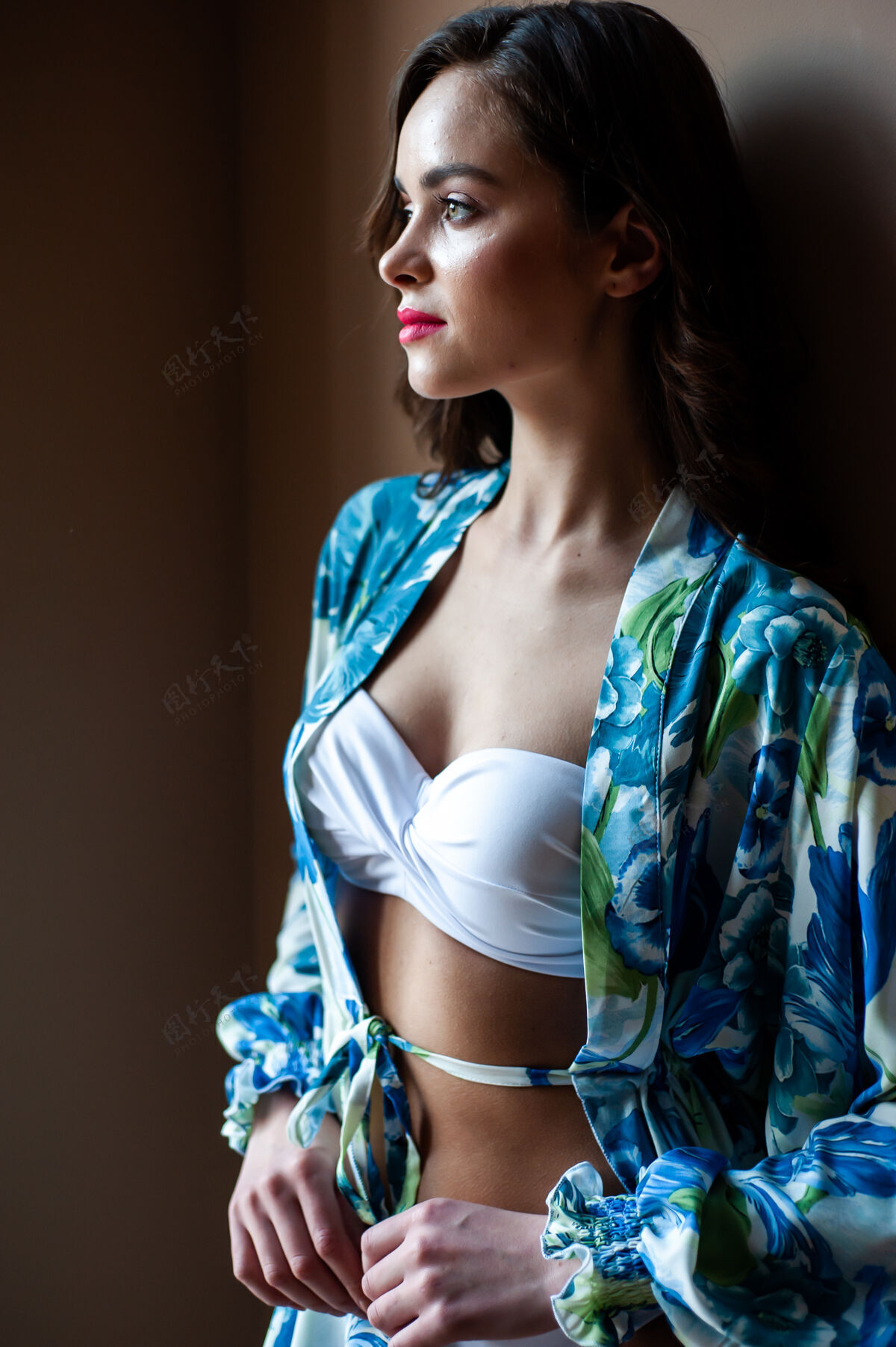 姿势美丽的微笑的女人穿着一件浅丝绸束腰外衣去海滩年轻束腰外衣季节