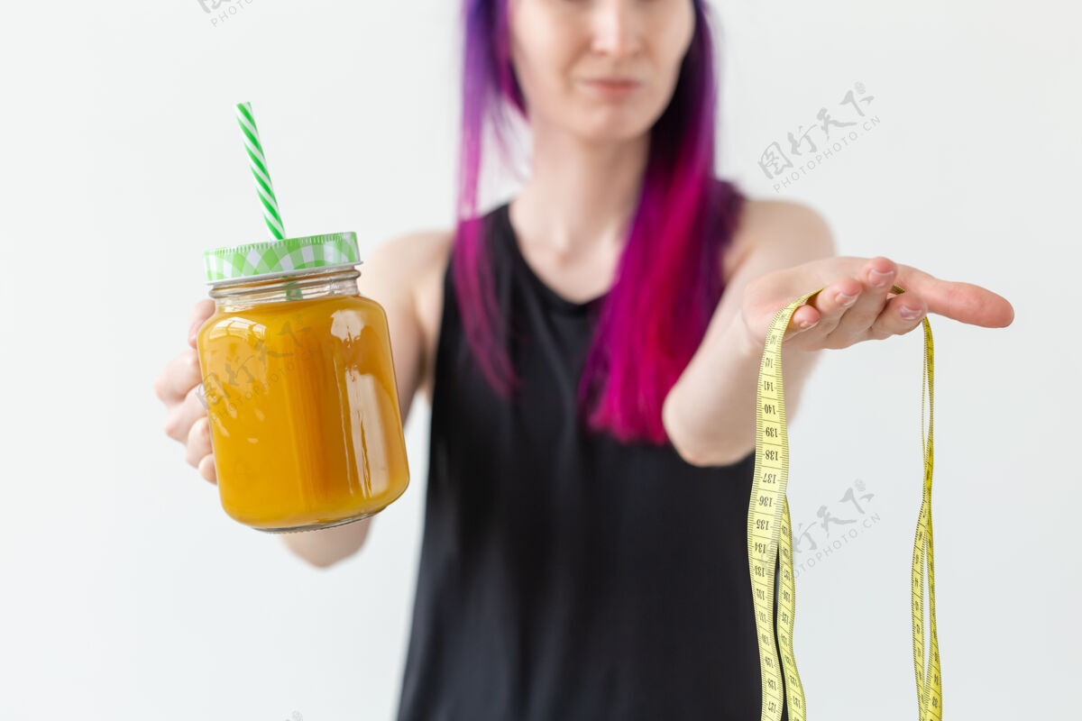 形状不明身份的年轻女子拿着一根吸管和卷尺 手里拿着水果蛋白汁动作强壮成人