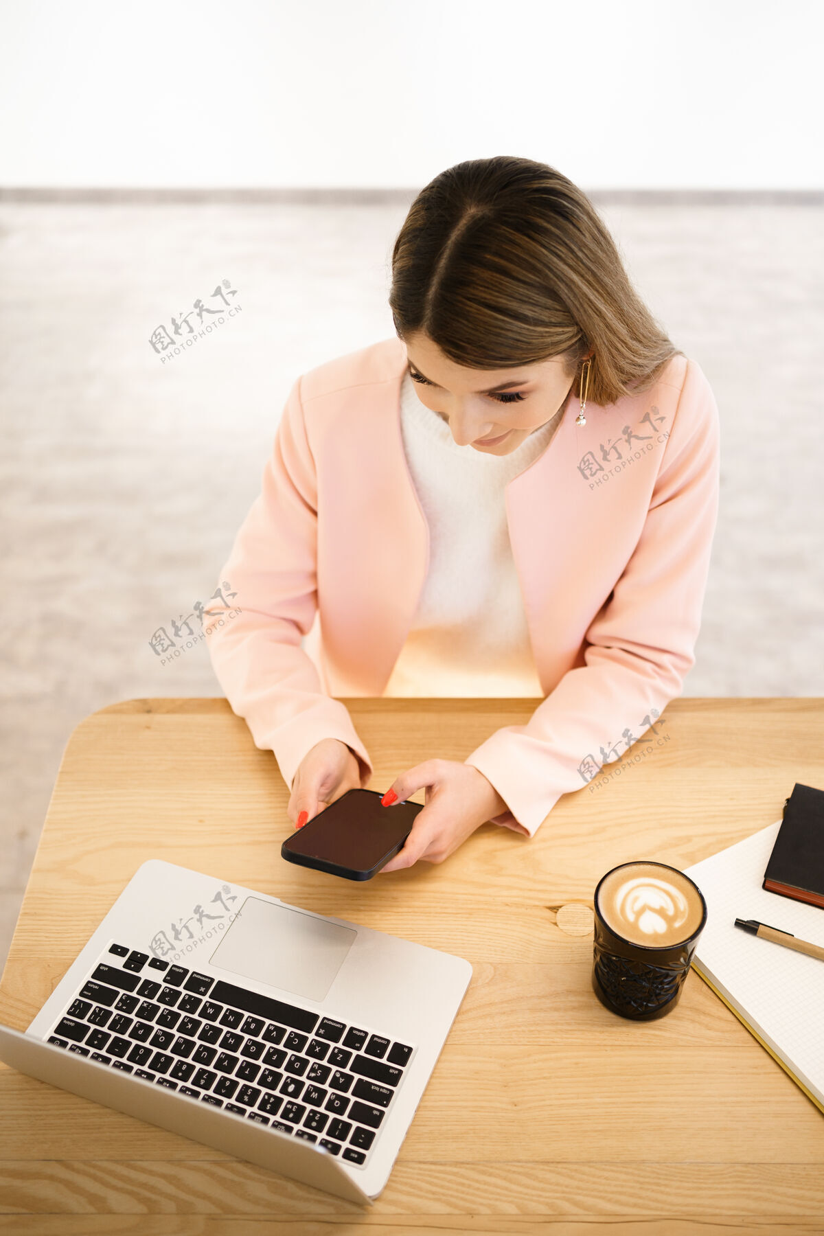 遥控一位面带坦诚微笑的女店员 在咖啡厅聊天 享受咖啡休息时间她穿着休闲的白色毛衣 粉色的夹克手机自拍白色毛衣
