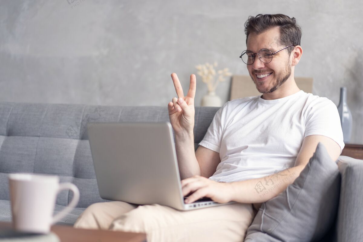 沙发快乐的年轻人坐在家里的沙发上用笔记本电脑视频聊天人互联网男性
