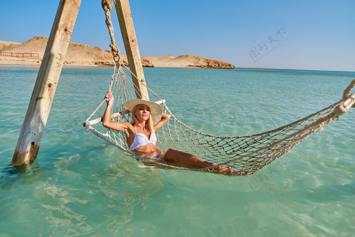 度假村旅行和度假的概念妇女放松吊床在海上海洋比基尼女人