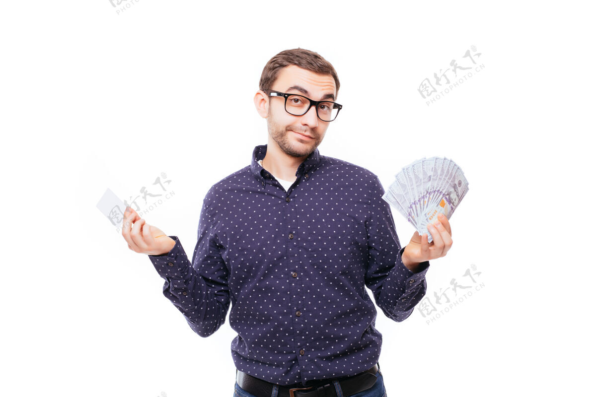 欢呼一个戴着眼镜的快乐微笑的男人的肖像 手里拿着一捆钞票 信用卡隔着白色的墙银行票据信贷