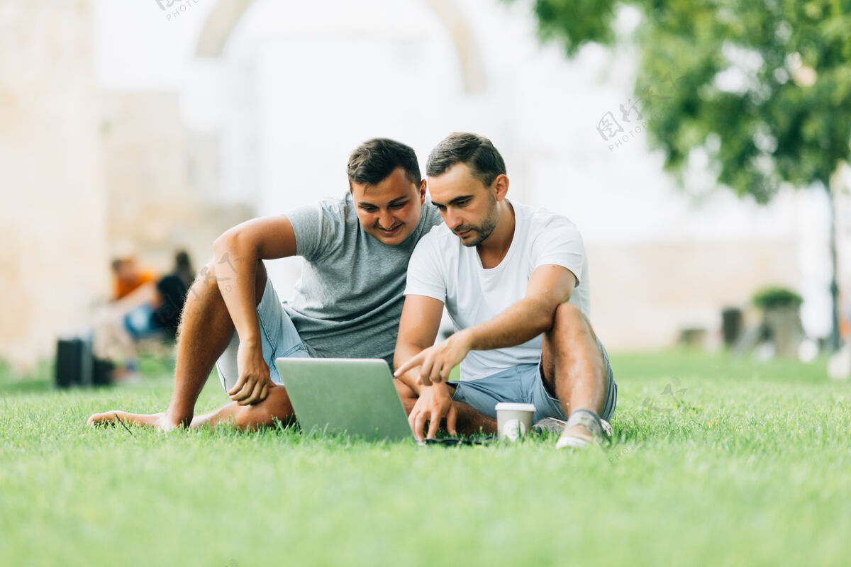 无线两个男人在公园的果岭上用笔记本电脑工作休闲自然花园