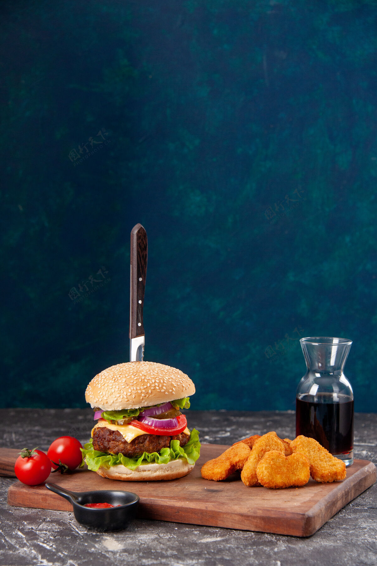食物刀在肉三明治和鸡块番茄干木板酱番茄酱在深蓝色的表面鸡肉美味餐
