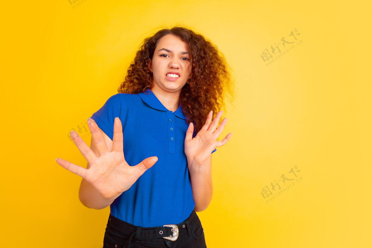 年轻拒绝 语焉不详黄色工作室背景上的白人少女肖像穿着衬衫的漂亮女性卷发模特人类情感的概念 面部表情 销售 广告 教育复制空间肖像专业人